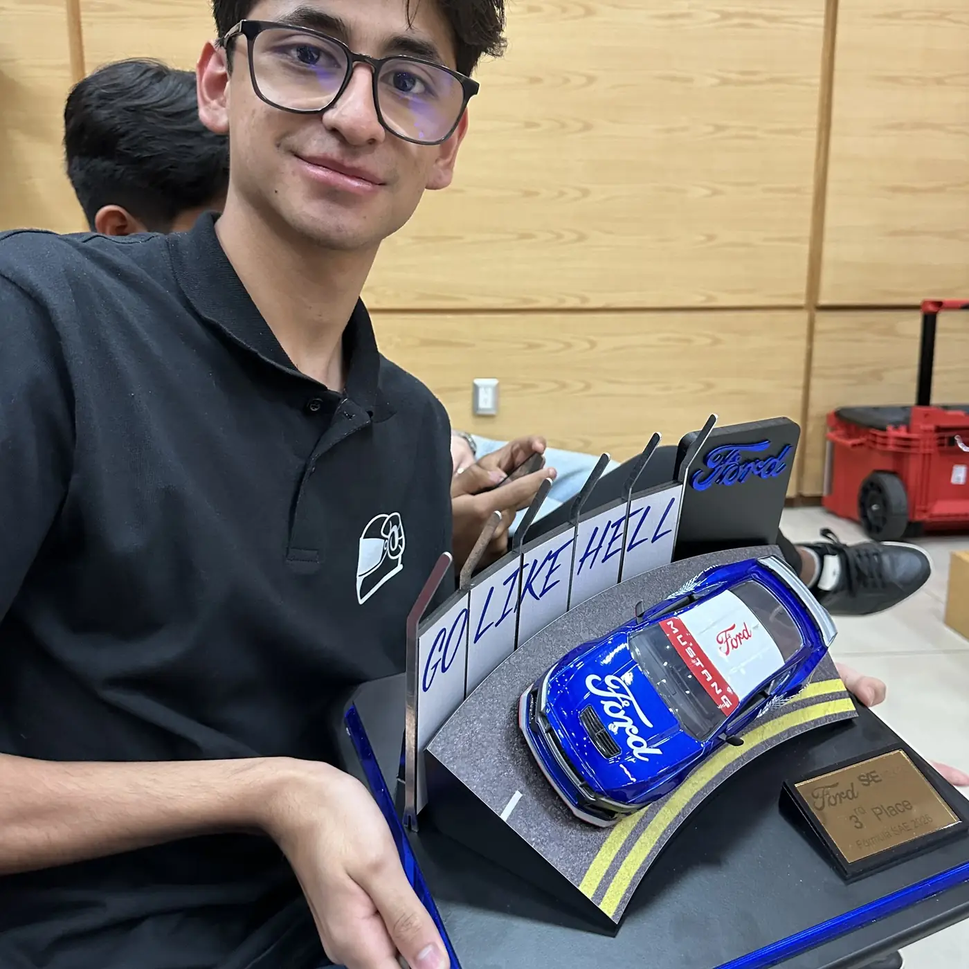 A team member holding the Ford trophy awarded for third place